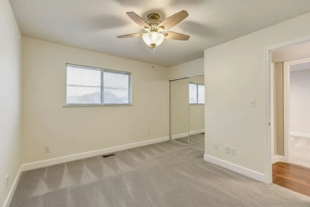 an empty room with windows and fan
