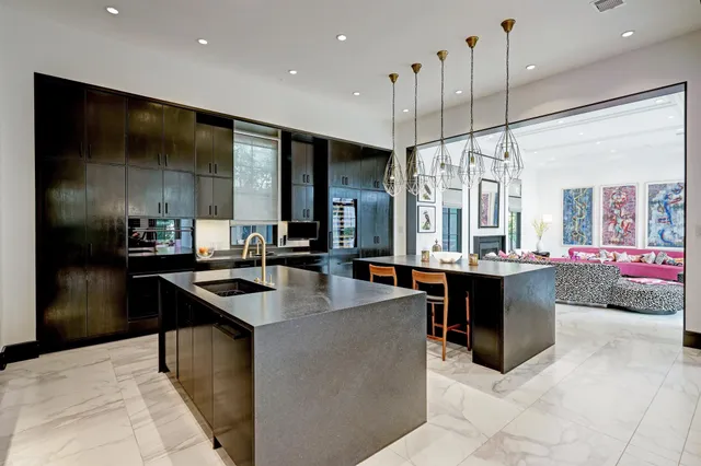 a kitchen with kitchen island granite countertop a sink a counter top space appliances and a view of living room