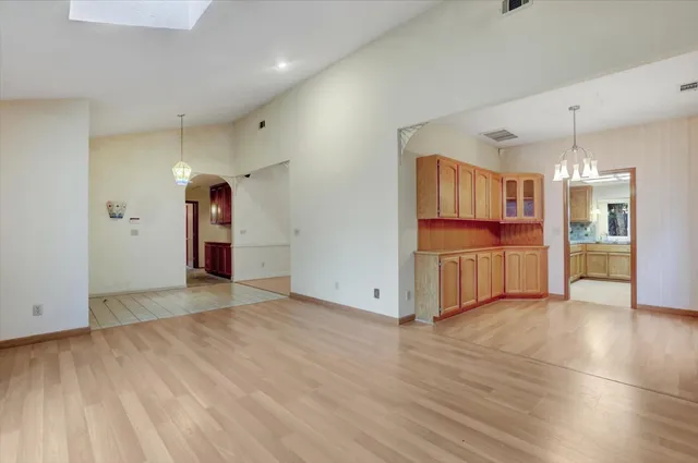 a view of an empty room with kitchen and a window