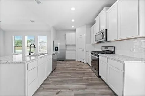 a large white kitchen with kitchen island a sink a stove and a refrigerator