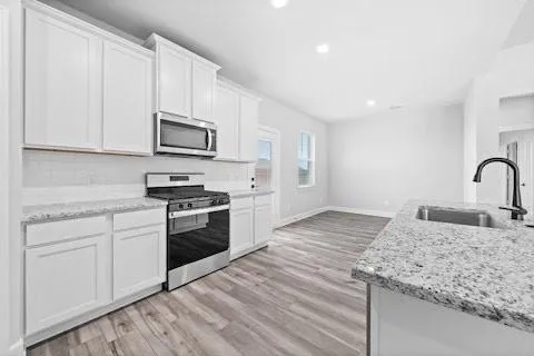 a kitchen with stainless steel appliances granite countertop a stove a sink and a microwave