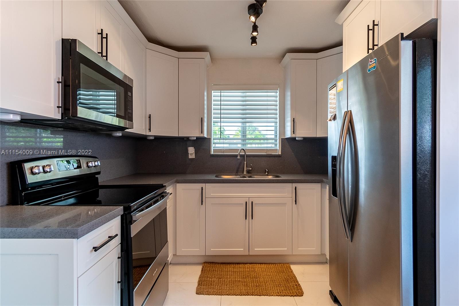 4235 East 9th Lane Hialeah, FL 33013 - Photo 13 of 34 a kitchen with stainless steel appliances granite countertop a refrigerator a stove a sink and dishwasher with wooden floor