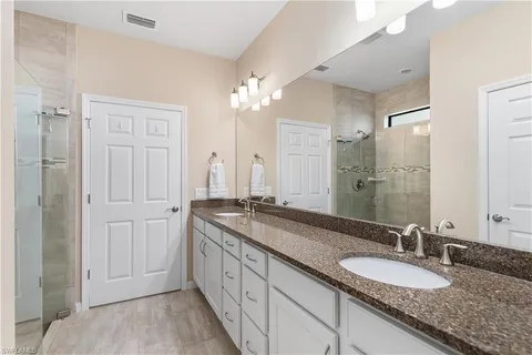 a bathroom with a granite countertop double vanity sink and a mirror