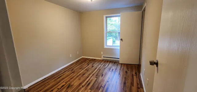 a view of an empty room with wooden floor and a window