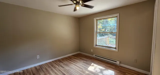 an empty room with a window and ceiling fan