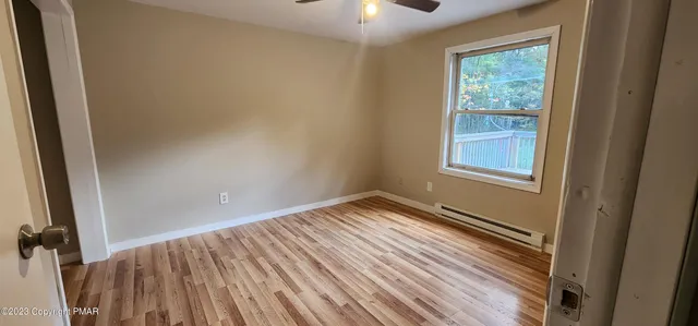 a view of an empty room with wooden floor and a window