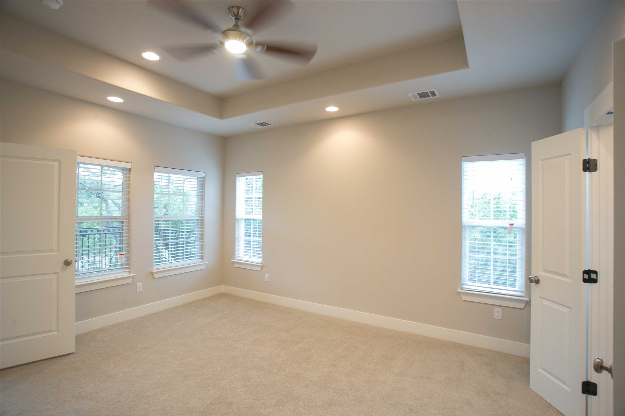 4301 Mansfield Dam Road, Unit 2102 Austin, TX 78734 - Photo 5 of 9 A spacious primary bedroom features soft carpeting, a ceiling fan, and ample natural light from multiple windows.