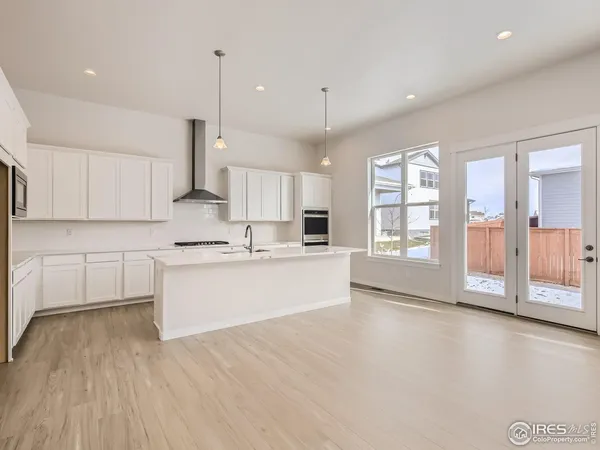 a large kitchen with cabinets wooden floor and a window