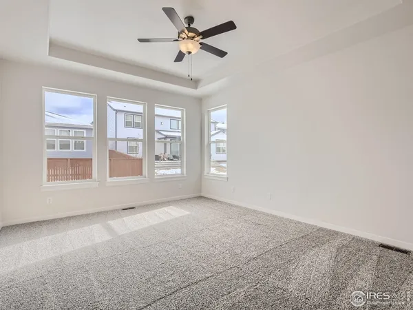 an empty room with chandelier fan and windows