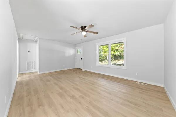a view of an empty room with wooden floor and a window