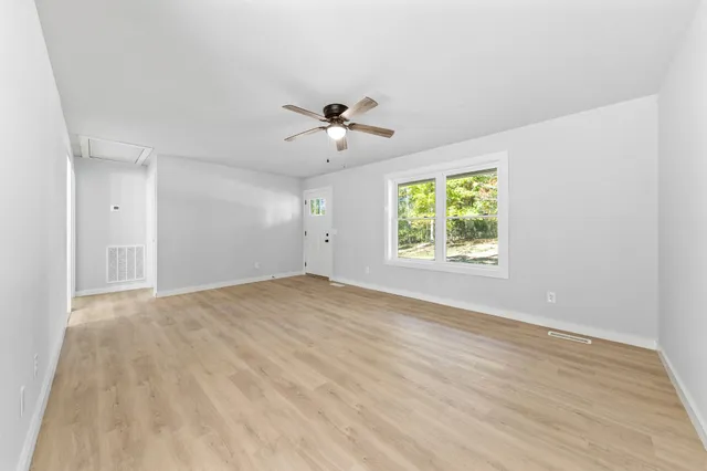 a view of an empty room with wooden floor and a window