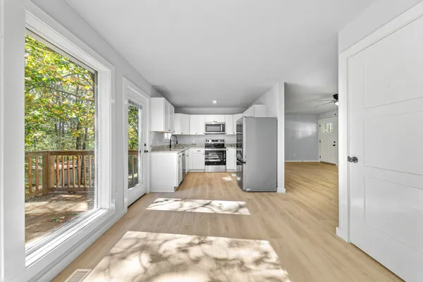 a view of an empty room with wooden floor and a ceiling fan