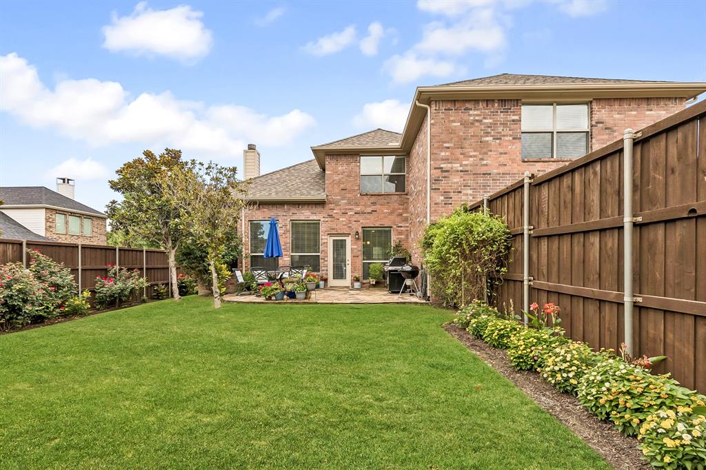 960 Remuda Road Frisco, TX 75033 - Photo 30 of 39 Spacious backyard featuring a substantial lawn, a stone patio, and mature landscaping