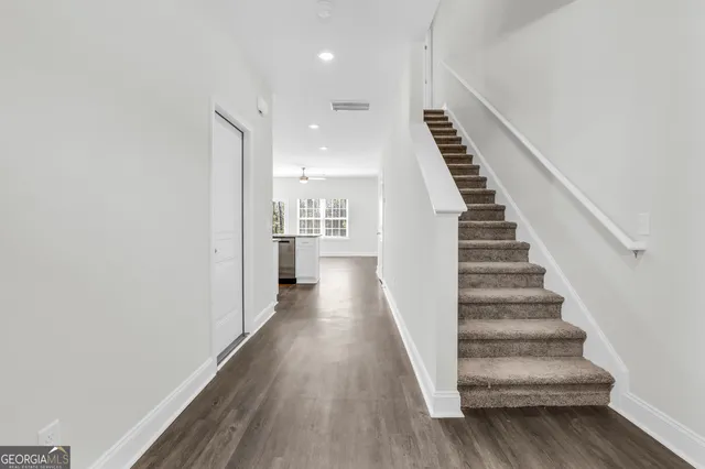 a view of a hallway with wooden floor and stairs