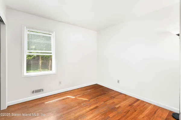an empty room with wooden floor and a window