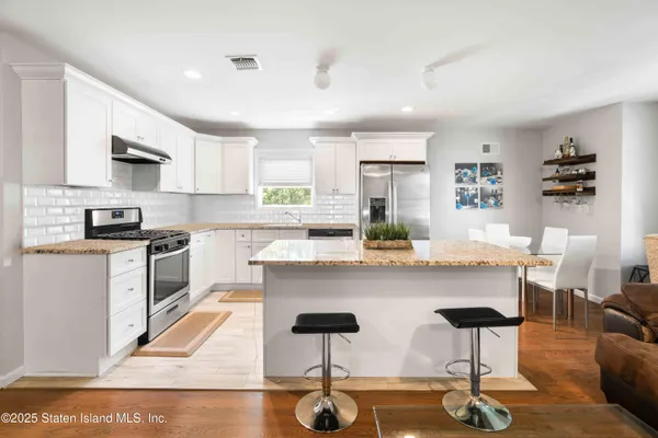a kitchen with stainless steel appliances kitchen island granite countertop a table chairs sink and cabinets