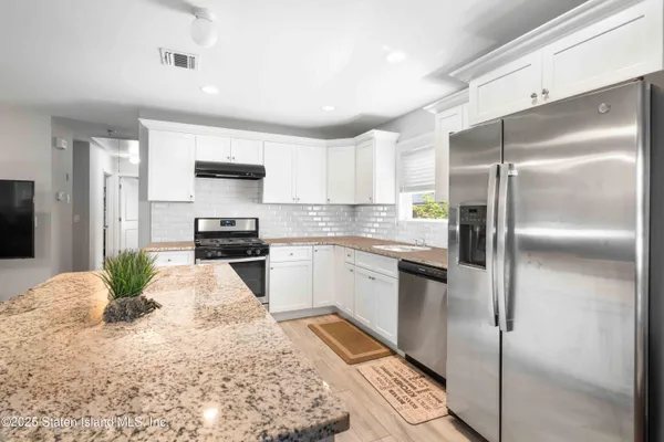a kitchen with granite countertop a refrigerator and a sink
