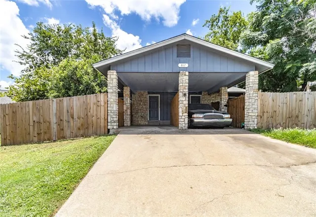 a view of a car park in front of house with wooden fence