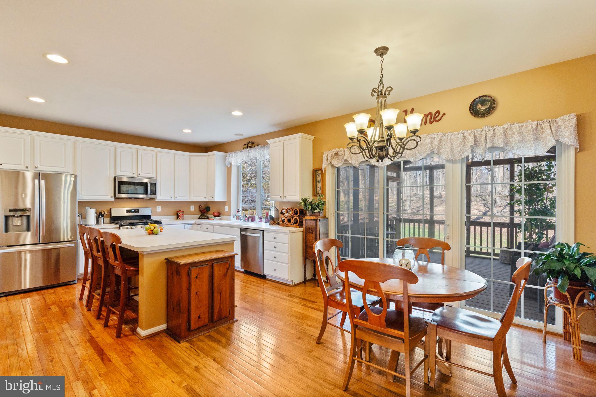 12298 Wake Forest Road Clarksville, MD 21029 - Photo 10 of 46 a kitchen with refrigerator a stove and a dining table with wooden floor