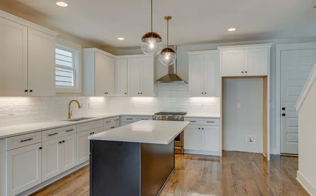 a kitchen with a sink a center island a stove cabinets and a window