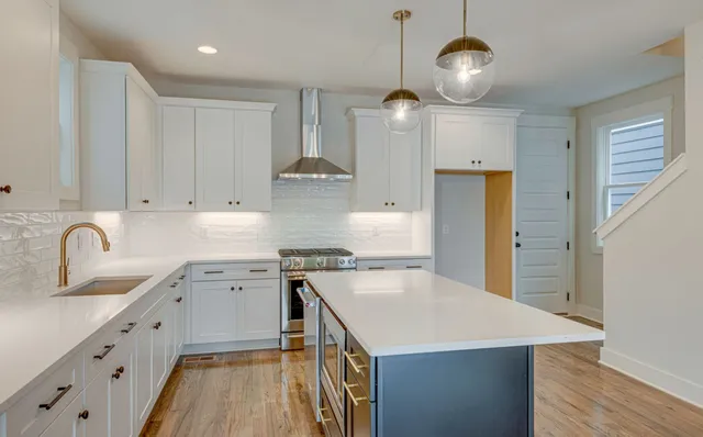 a kitchen with stainless steel appliances granite countertop a sink a stove and a wooden floors