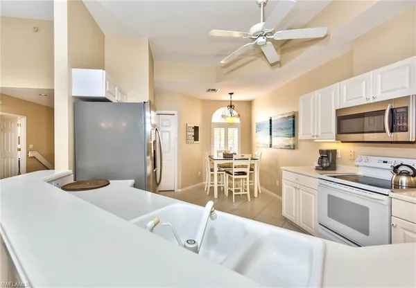 a kitchen with stainless steel appliances granite countertop a sink a stove a dining table and chairs