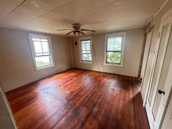 a view of an empty room with wooden floor and window