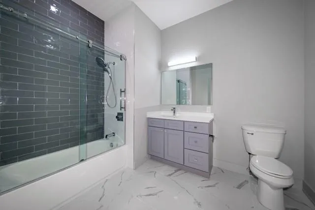 a bathroom with a granite countertop toilet a sink and shower