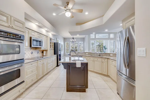 a kitchen with stainless steel appliances granite countertop a refrigerator a stove top oven a sink dishwasher and white cabinets