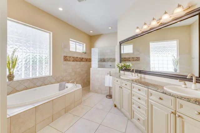 a spacious bathroom with a double vanity sink a mirror and a bathtub