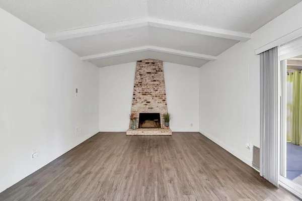 an empty room with wooden floor a fireplace and windows