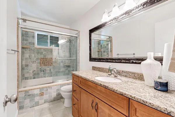 a bathroom with a granite countertop sink a toilet and shower