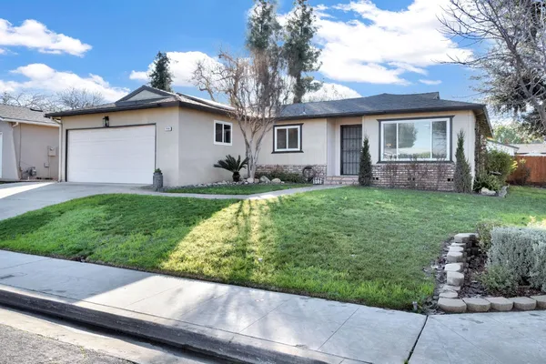 a front view of a house with a garden and trees