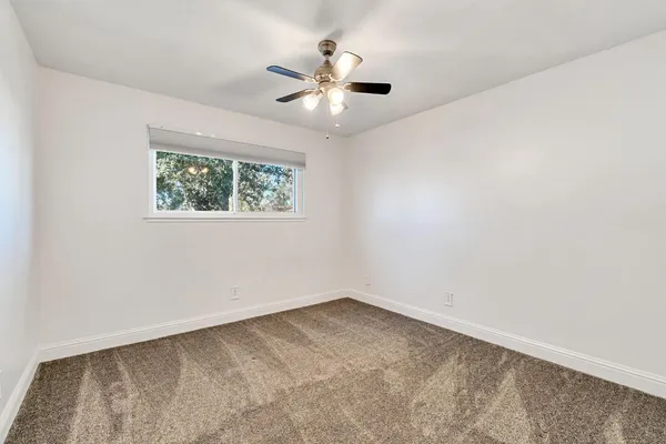 an empty room with a window and a ceiling fan