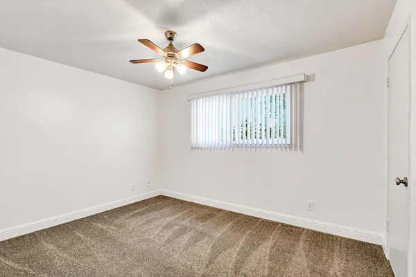 an empty room with windows and fan
