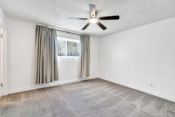 an empty room with a ceiling fan and windows