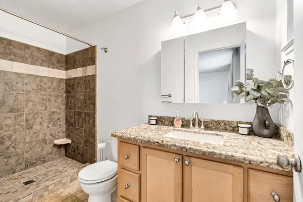 a bathroom with a granite countertop sink a toilet and a mirror