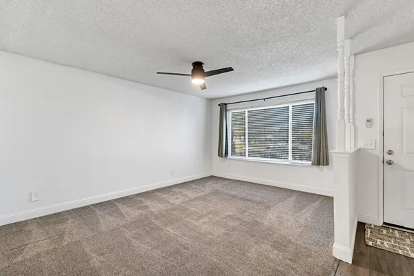an empty room with ceiling fan and windows