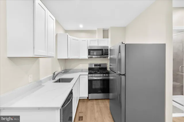 a kitchen with a refrigerator a sink and dishwasher with wooden floor