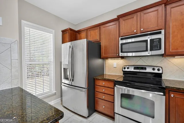 a kitchen with granite countertop a refrigerator stove and microwave
