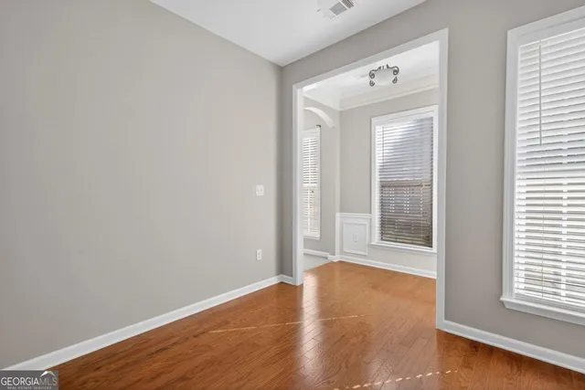 an empty room with wooden floor and windows