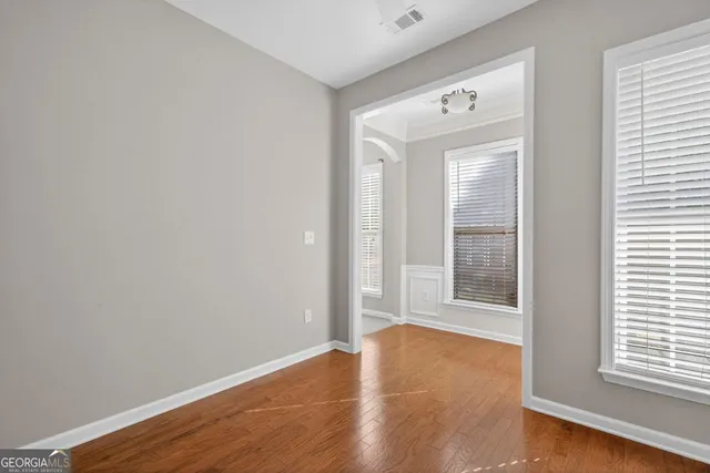 an empty room with wooden floor and windows