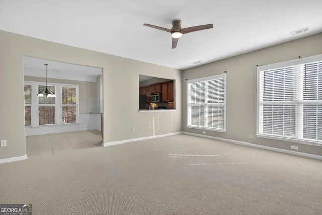 a view of an empty room with a window and a kitchen