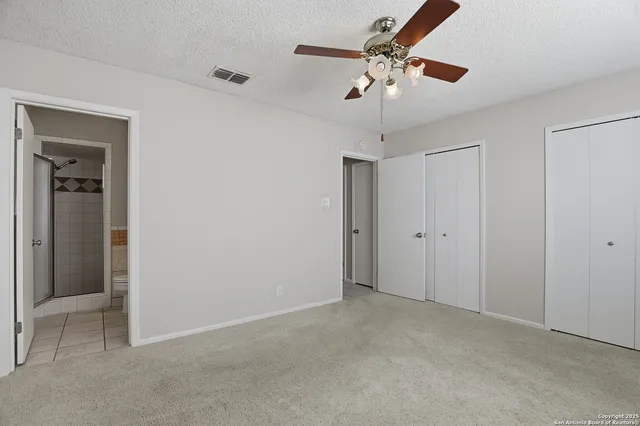 a view of an empty room with a chandelier fan