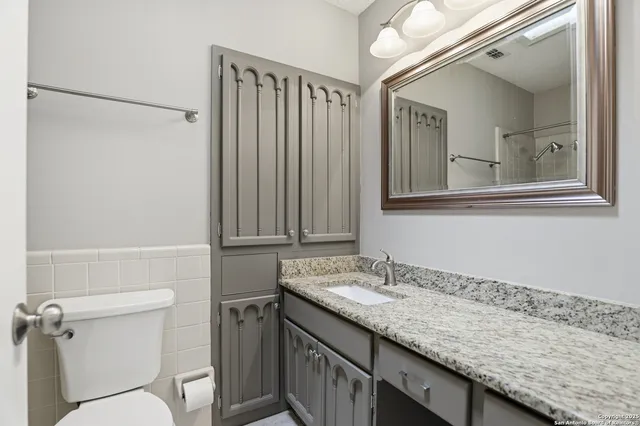 a bathroom with a granite countertop sink toilet and shower