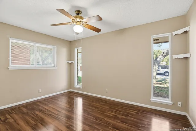 a view of an empty room with wooden floor and a window