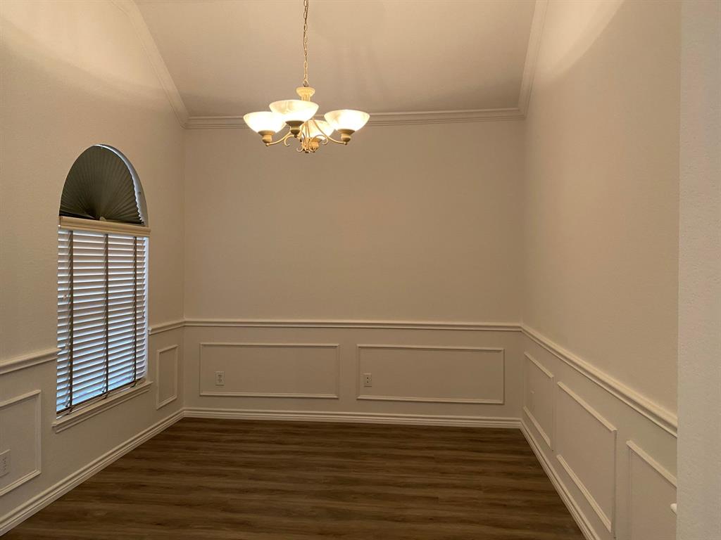 9814 Glenshee Drive Rowlett, TX 75089 - Photo 12 of 25 Unfurnished dining area with a chandelier, dark wood-style flooring, a decorative wall, ornamental molding, and wainscoting