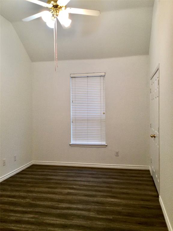 9814 Glenshee Drive Rowlett, TX 75089 - Photo 13 of 25 Spare room featuring lofted ceiling, dark wood-style flooring, and a ceiling fan