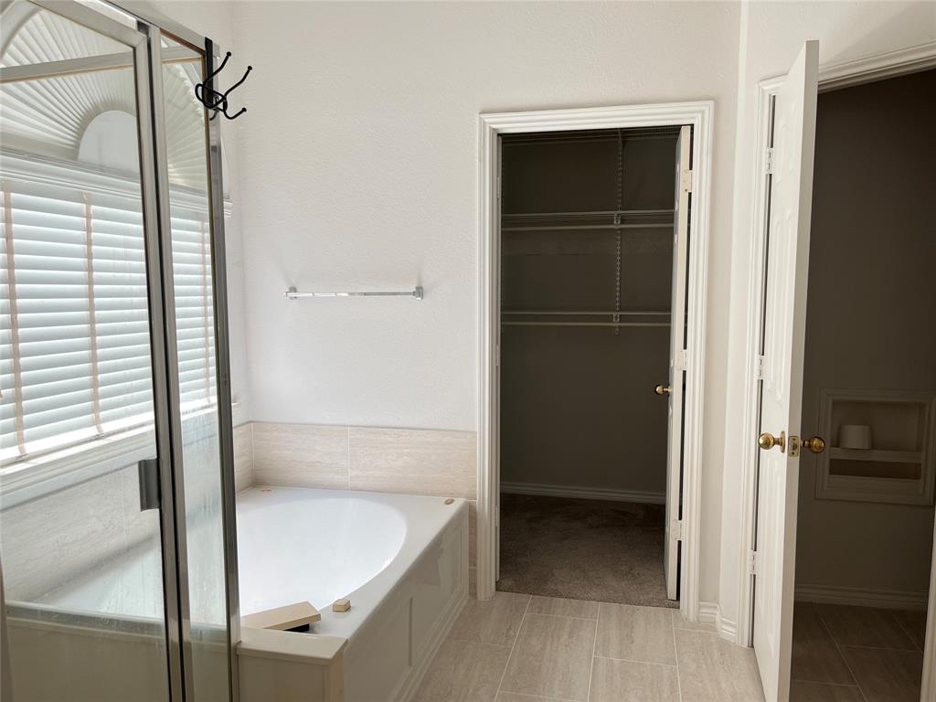 9814 Glenshee Drive Rowlett, TX 75089 - Photo 16 of 25 Full bath featuring a bath, a spacious closet, and a shower with shower door