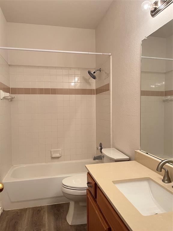 9814 Glenshee Drive Rowlett, TX 75089 - Photo 17 of 25 Full bathroom with a textured wall, vanity, shower combination, and dark wood-style floors